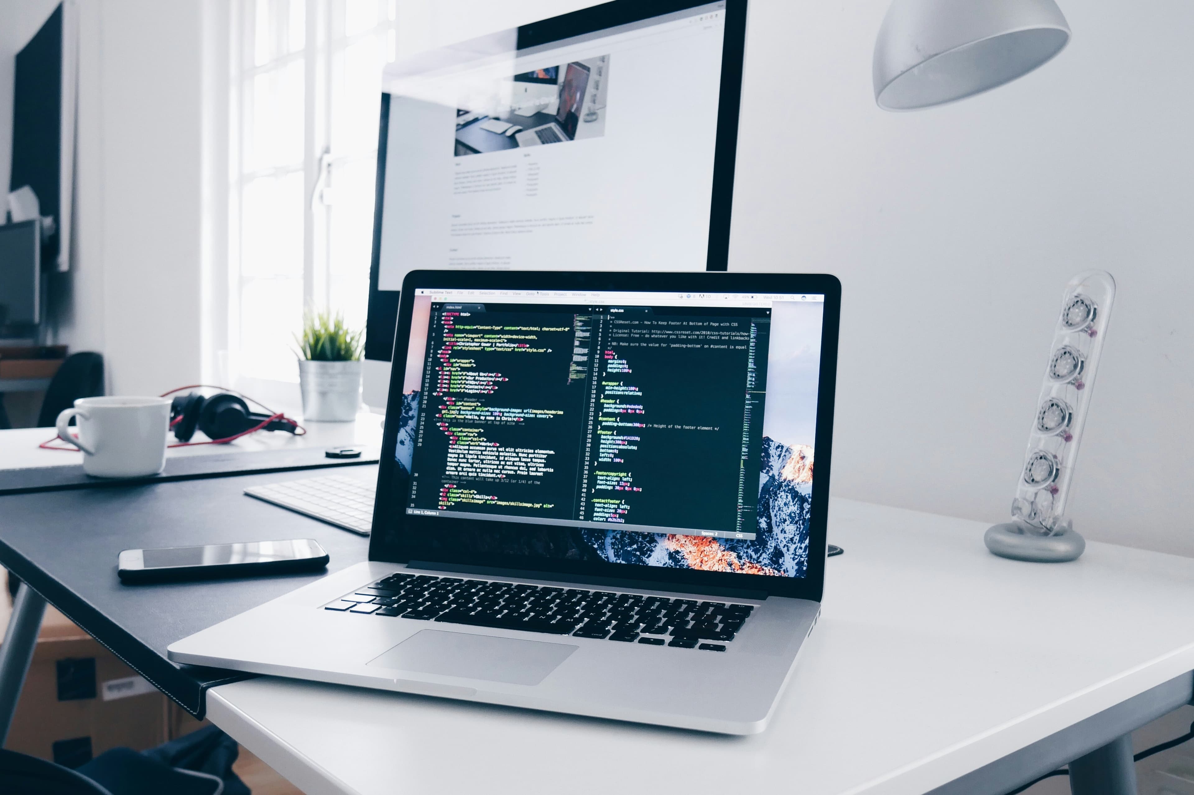 MacBook showing lines of code on a busy developer desk