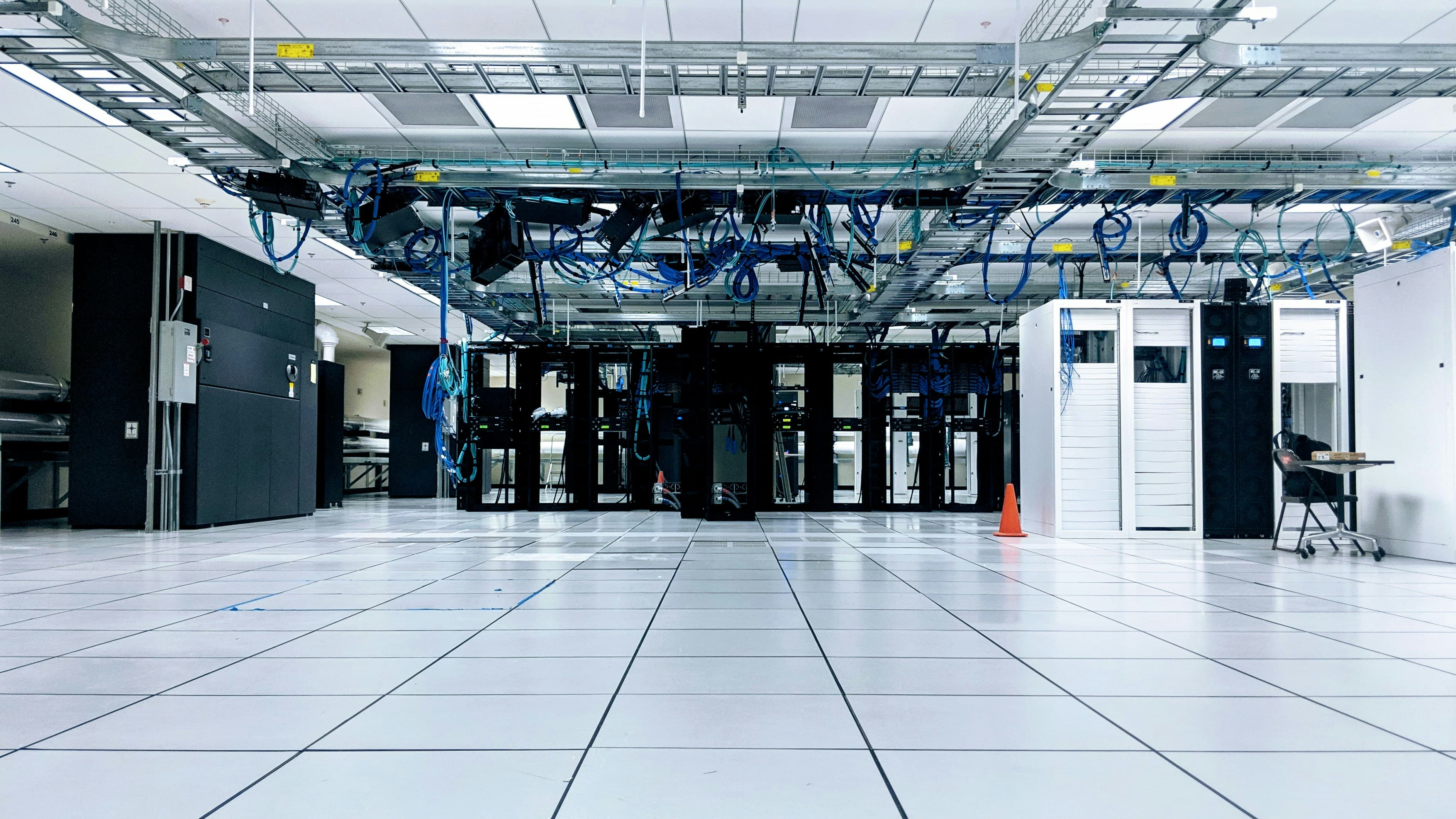 Rows of server cabinets in a data center connected by blue network cables