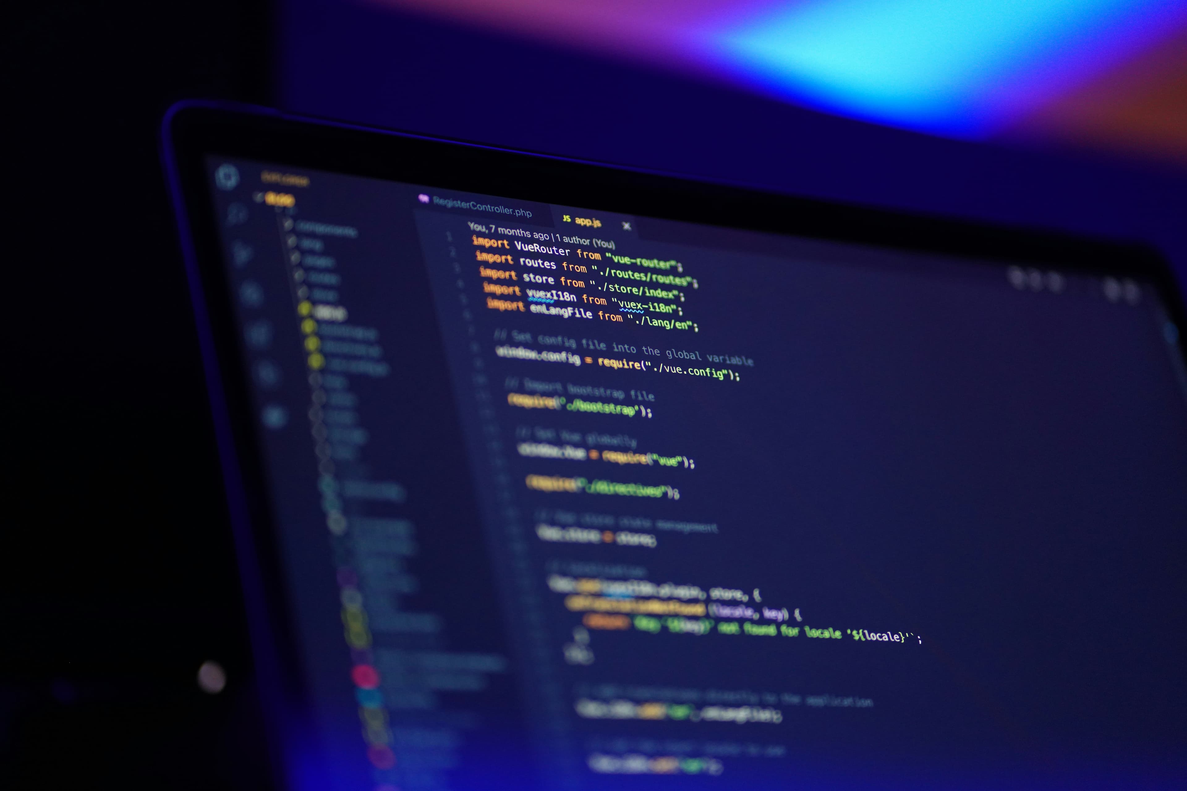 Laptop screen showing colourful source code in a dark code editor